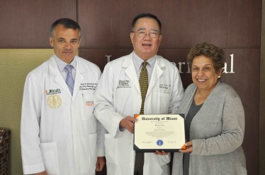 UM President Donna E. Shalala, right, and Miller School Dean Pascal J. Goldschmidt, left, present renowned ophthalmologist David T. Tse with his UM undergraduate degree during an ophthalmology grand rounds session held on July 11.